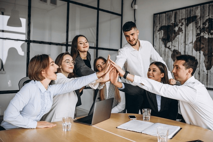 workers high fiving each other at a meeting