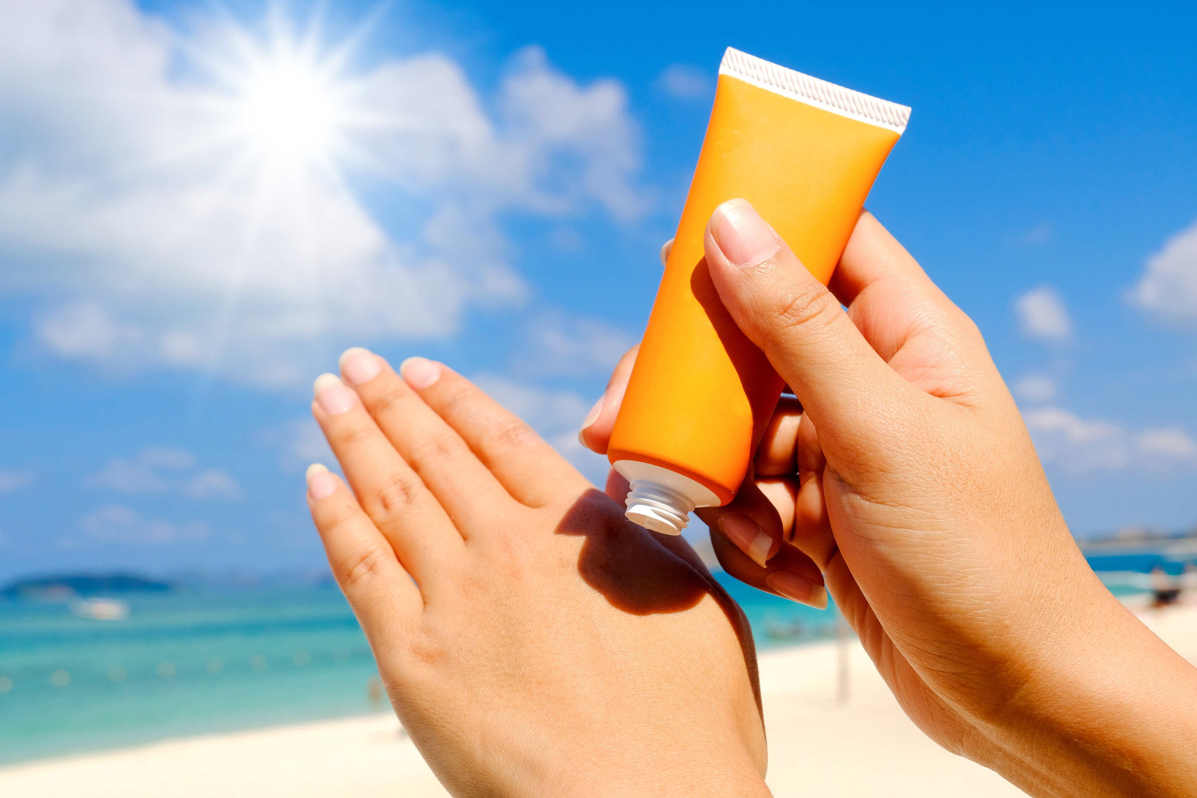 an orange sunscreen about to be rubbed on someone's hand