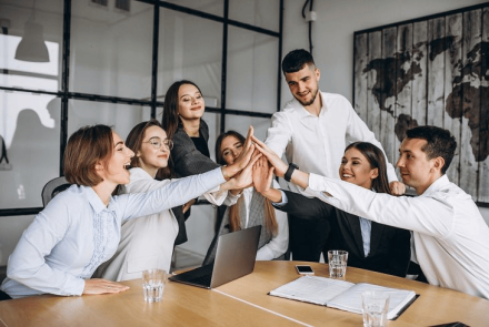 workers high fiving each other at a meeting