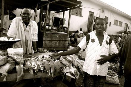 a man standing infront of  a meat seller