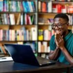 Happy young black male student in a library 