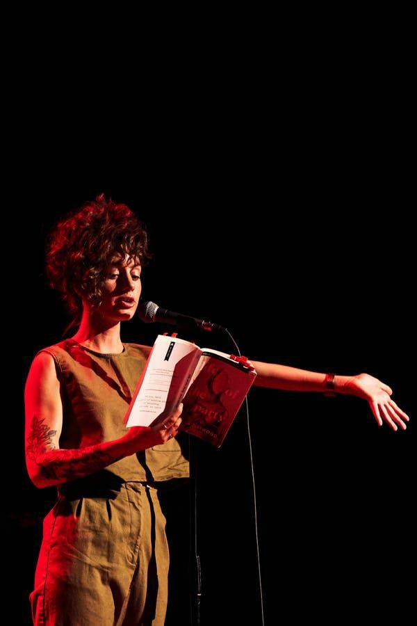 A woman standing a saying a poem near a mic